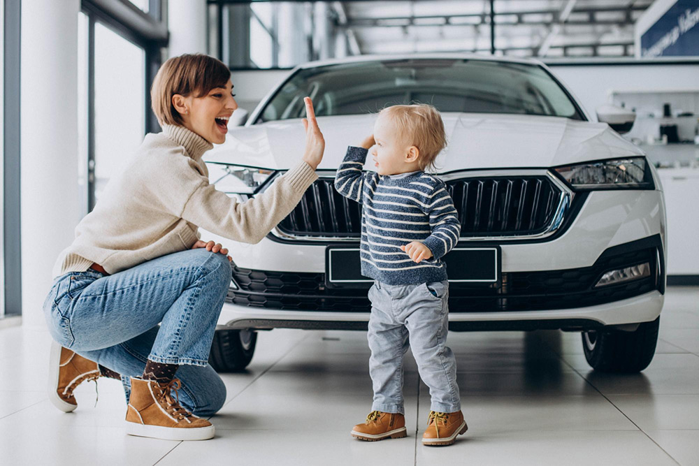 high five of mother with child in front of car